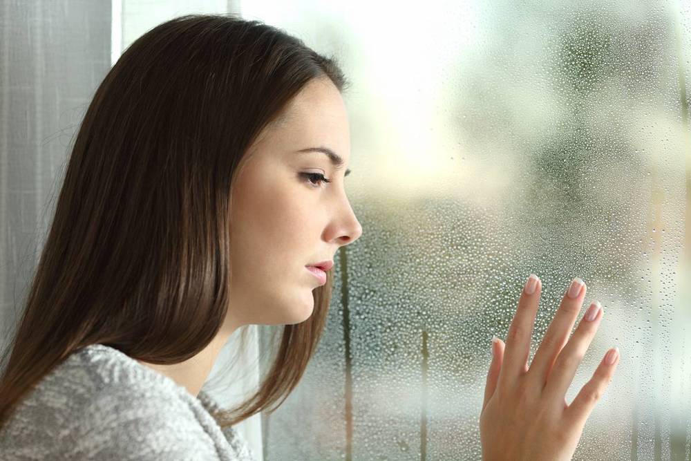 stanchezza invernale donna triste guarda finestra metre piove