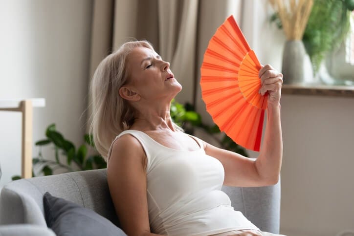 sintomi della menopausa donna con vampate di calore si sventola con un ventaglio
